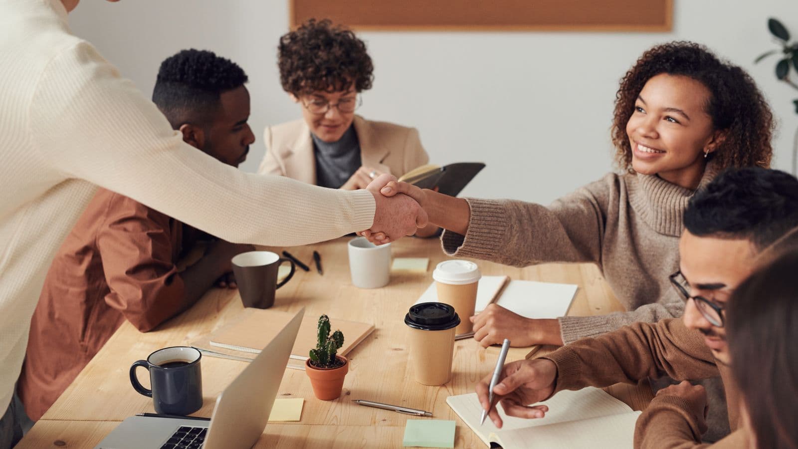 A new team member shaking hands with a colleague across a desk during a first meeting